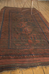 Secure fringe and patterned border of the vintage Belouch rug, in madder red and navy.