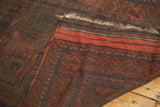 Belouch rug's folded edge showing geometric patterns in madder red, navy, brown tones.