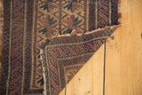 Antique Belouch rug corner reveals geometric starburst motifs, worn fringed edge, and hand-knotted backing.