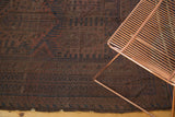 Woven end and geometric patterns of a vintage Belouch carpet in faded red and navy.