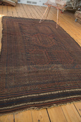 Fringed end of the vintage Belouch carpet, showing horizontal stripes in faded red and navy.