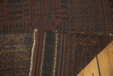 Folded vintage Belouch carpet displaying striped foundation and faded red, navy pile patterns.