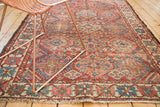 Vintage Baktiari rug with repeating diamond pattern, cherry red, sky blue hues, and soft fringe.