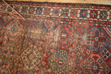 Worn Baktiari rug section with geometric diamond pattern in cherry red, sky blue, emerald green.