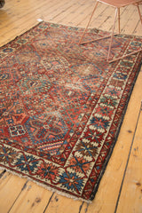 Distressed vintage Baktiari rug corner showing geometric border in cherry red, sky blue, and ivory.