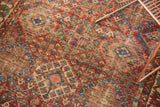 Distressed vintage Baktiari rug texture showing cherry red, sky blue, and ivory patterns.