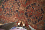 Vintage Caucasian rug, textured brick red field with bold navy blue geometric medallions.