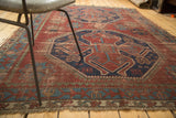 Vintage Caucasian rug's geometric border, fringe, and time-softened brick red pile.