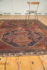 Geometric motifs and secured edge of vintage Caucasian rug in brick red, navy, sky blue.