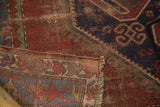 Hand-knotted vintage Caucasian rug detail: geometric patterns, wear to foundation, and fringed edge.