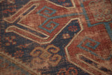 Storied texture with geometric navy, brick red, and sky blue patterns on a vintage Caucasian rug.