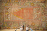 Antique Oushak prayer rug with faded orange field, even wear, visible foundation.