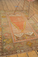Antique Oushak prayer rug: worn fringe and geometric borders in terra cotta, saffron, gray.