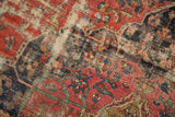 Antique Farahan carpet's ornate curvilinear patterns in blush rose, navy, and aged green, with evident wear.