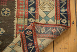 Folded antique Caucasian rug revealing hand-knotted foundation and geometric patterns.