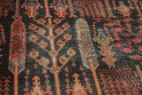 Angled detail of antique Bijar rug's forest foliage, dark ground, and worn texture.