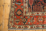 Antique Bijar rug corner, showing distressed madder red field and beige floral border.