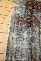 Tattered corner of vintage Mahal carpet, showing distressed pile and faded floral motifs.