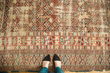 Intricate geometric borders and tattered end of an antique Caucasian carpet in reds and blues.