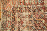 Detail of antique Caucasian carpet showing exposed foundation and wear on the repeating lattice motif.