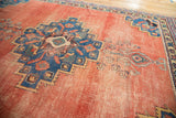 Distressed antique Afshar rug corner, showing geometric patterns, navy border, and blush field.