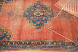 Distressed antique Afshar rug's macramé end, geometric navy border, and blush terra cotta field.