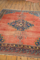 Distressed terra cotta field and intricate blue geometric border of an antique Afshar rug.