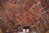Vintage Heriz carpet with dark blush brick red field, geometric vinery, and visible pile wear.