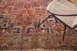 Hand-knotted Heriz carpet corner, geometric vinery in blush brick red, navy, and oxidized green.