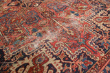 Heriz carpet with geometric vinery and budding flowers in red, navy, beige, showing areas of pile wear.