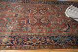Distressed vintage Heriz carpet features a brick red field with angular motifs and navy border.