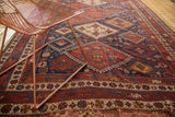 Hand-knotted antique Afshar carpet corner, geometric patterns in rich red and blue, with tattered fringe.
