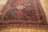 Afshar carpet end with geometric motifs, revealing unrestored tattered edge and holes.