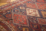 Antique Persian Afshar rug's geometric diamond patterns in madder red and rich indigo, showing border tatter.