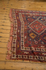 Tattered left edge of the antique Afshar carpet, showing holes and geometric border patterns.