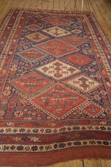 Tattered end of antique Afshar carpet, with madder red and indigo geometric patterns.
