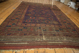 Plain-woven end of antique Belouch carpet, showing recessed pile, madder red, and navy geometric patterns.
