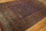 Visible patina on the antique Belouch carpet's geometric border, featuring madder red and navy patterns.