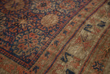 Intricate geometric patterns in time-softened navy, madder red, and brown on antique Belouch carpet.
