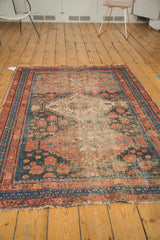 Tattered end of a vintage Afshar rug, displaying rich navy blue and brick red borders.