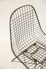 Angled profile of the Eames wire chair showing the sculptural curve of its black metal grid.