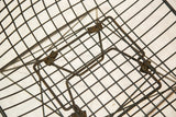 The intricate wirework and hardware of the Eames chair's cat's cradle base.