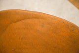 Close-up of the Eames chair's original orange wool seat cover showing stains and texture.