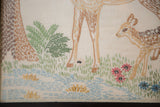 Vintage embroidery art detail showing baby deer, pink flowers, green grass, and blue water.