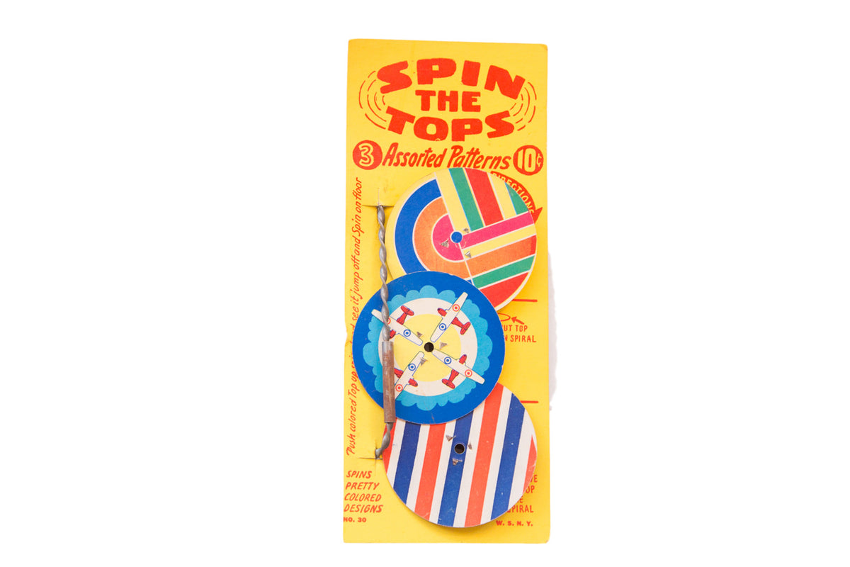 Mid Century Spin the Tops toy featuring colorful stripes, spirals, and airplane graphics.
