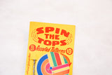 Yellow packaging detail of vintage Spin the Tops toy, red text, colorful design.