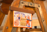 Mid Century Bubble King toy packaging close-up, purple text, pink bubble wand.