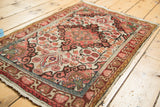 Vintage Sarouk rug angled view, with wine red scrolling medallion and ivory floral field.