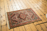Hand-knotted Sarouk rug corner showing blush, ivory, and burgundy floral tendrils.