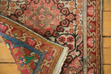 Turned corner of vintage Sarouk rug revealing blush floral pile, blue-red foundation, and ivory fringe.